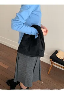 Detailed side view of black suede hobo bag showing minimalist slouchy silhouette