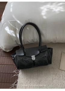 Close-up of retro black shoulder bag featuring matte leather texture and silver metal buckle