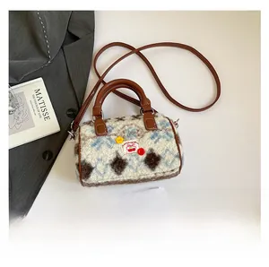 Detail view of plush cow pattern Boston bag with cherry patch and leather straps