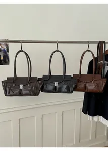 Three vintage tote bags in brown, black, and caramel hanging on a metal rack display