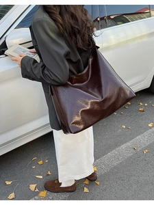 Detail of a large dark brown tote bag in glossy oil-wax leather for urban commuting