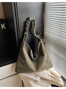 Detail der olivgrünen Handtasche mit gerafftem Griff, Kordelzug-Schleifen und Wildlederoptik