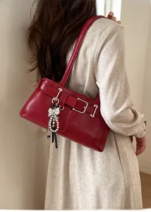 Detail view of deep red underarm bag with glossy finish and pearl bow charm