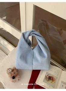 Close-up of knotted handle detail on light blue suede slouchy shoulder cloud bag