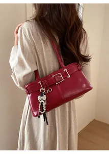 Detail of red vintage underarm bag with metal buckle and elegant pearl bow charm