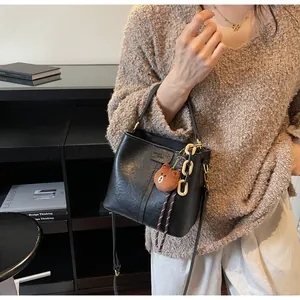 Detail view of black matte leather bucket bag with chain strap and teddy bear charm