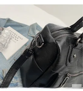 Close-up of shiny black leather handbag with silver metallic zippers and strap buckle