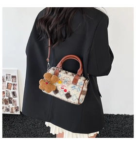 Detail of plush boston bag with cherry patch, leather handles and bear keychain