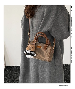 Detail einer braunen Boston-Tasche mit süßem Teddybär-Anhänger und strukturiertem Stoff
