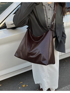 Close-up of a large dark brown hobo tote bag with a glossy wrinkled texture and adjustable strap