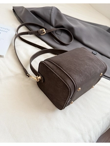 Detailed view of dark brown leather Boston bag showing gold hardware and metal feet
