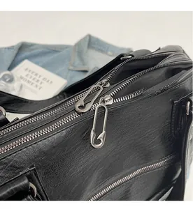 Detail of double zipper closure with unique silver safety pin hardware on black leather bag