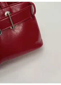 Detail of red glossy leather handbag with silver metallic buckle and stitching