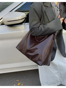 Detail of glossy dark red-brown tote bag with vintage wrinkled texture and high shine
