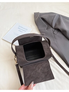 Top view of an open dark grey box-style handbag with golden metal clasps and textured finish