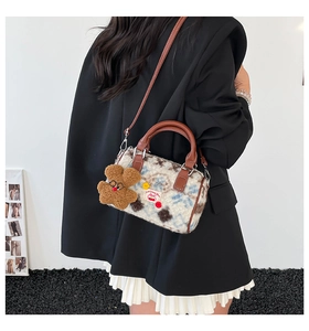Detailed view of plush Boston bag featuring cow pattern with cute bear charm and leather strap