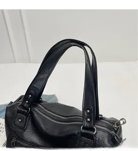 Close-up of black pebble leather tote featuring triple zippers and reinforced rivet handles