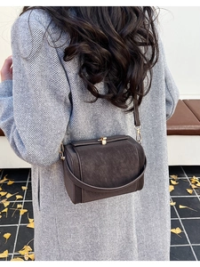 Detail of dark brown leather crossbody bag with vintage gold hardware on model