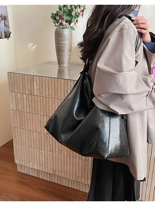 Side view of large black faux leather tote bag showing soft texture and natural drape