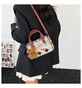 Detail of plush cow print Boston bag with bear charm and cherry patch embroidery