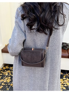 Retro dark brown crossbody bag worn with a grey long coat in an autumn street setting