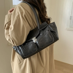Minimalist black faux leather tote bag with dual front pockets and silver metal buckles
