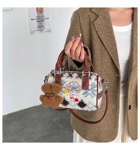 Detail of plush boston bag with cherry patch, bear charm and faux leather handle