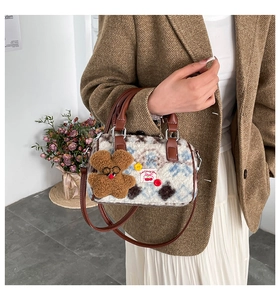 Close-up of plush floral Boston bag with brown leather handles and cute bear charm