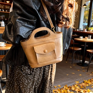 Vintage khaki PU leather bucket bag with top handle and strap in an autumn cafe setting