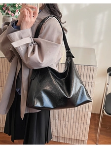 Detail of black glossy tote bag with adjustable silver buckle strap on a model