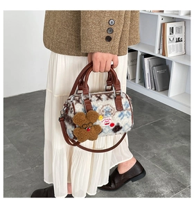 Detail of plush cow print Boston bag with leather handles and a cute bear charm