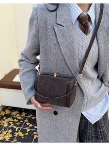 Detail view of a vintage dark brown satchel bag with retro metal clasp and matte finish