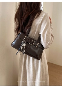Detail of dark brown glossy underarm bag with silver buckle and star tassel charm