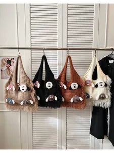 Close-up of knit tote bags with 3D cartoon dog charms and fringe details in four colors