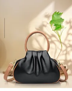 Detail of black cloud bag with lychee texture leather and brown circular handles
