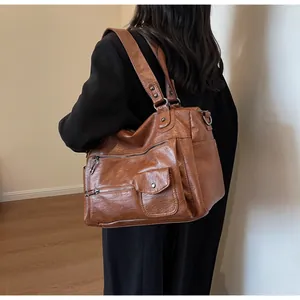 Rear view of brown leather tote bag with functional zippers on casual black suit