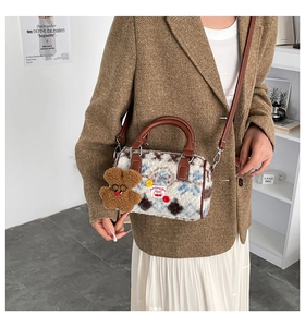 Detail of plush cow pattern bag with brown leather handles and cute bear charm