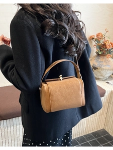 Close-up of brown vintage leather crossbody bag featuring a golden twist lock closure