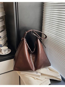 Close-up of a large oil wax brown tote bag showing glossy texture and adjustable strap