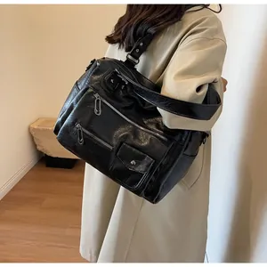Detailed view of black vintage PU leather handbag with wide shoulder strap and multi-pocket design