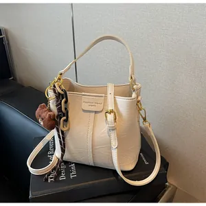 Detail of cream bucket bag with golden hardware and fashion trend engraved logo