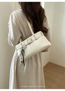 Minimalist white shoulder bag detail featuring buckle strap and chic tassel pendant accessory