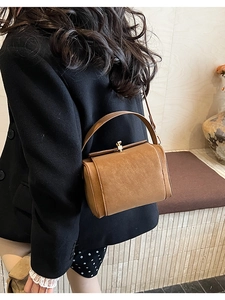 Side view of a vintage brown leather crossbody bag with a curved handle and gold clasp