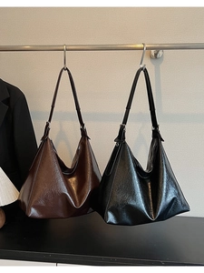 Detail view of brown and black hobo bags with oily leather texture and silver buckles
