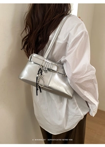 Detail view of silver underarm bag featuring a metal buckle and bow charm decoration