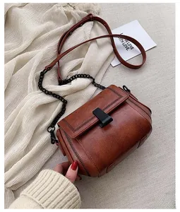 Detail of vintage brown textured leather crossbody bag with braided trim and chain strap