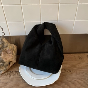 Detail of minimalist black faux suede hobo bag with vintage texture and center stitching