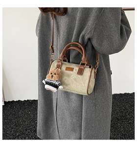 Detail der graugrünen Boston-Tasche mit Bärenanhänger getragen zum grauen Mantel