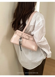 Pink leather baguette bag detail with metallic buckle and beaded bow charm pendant