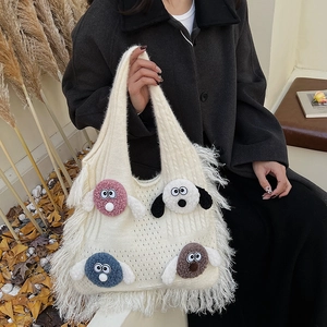 White knit tote bag with colorful dog embroidery and wool tassels in an autumn setting